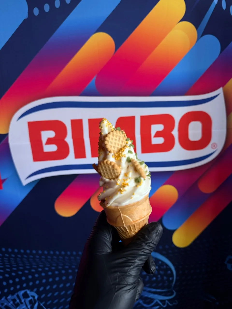 Detalle de un cono de helado con complementos frente al logotipo de Bimbo